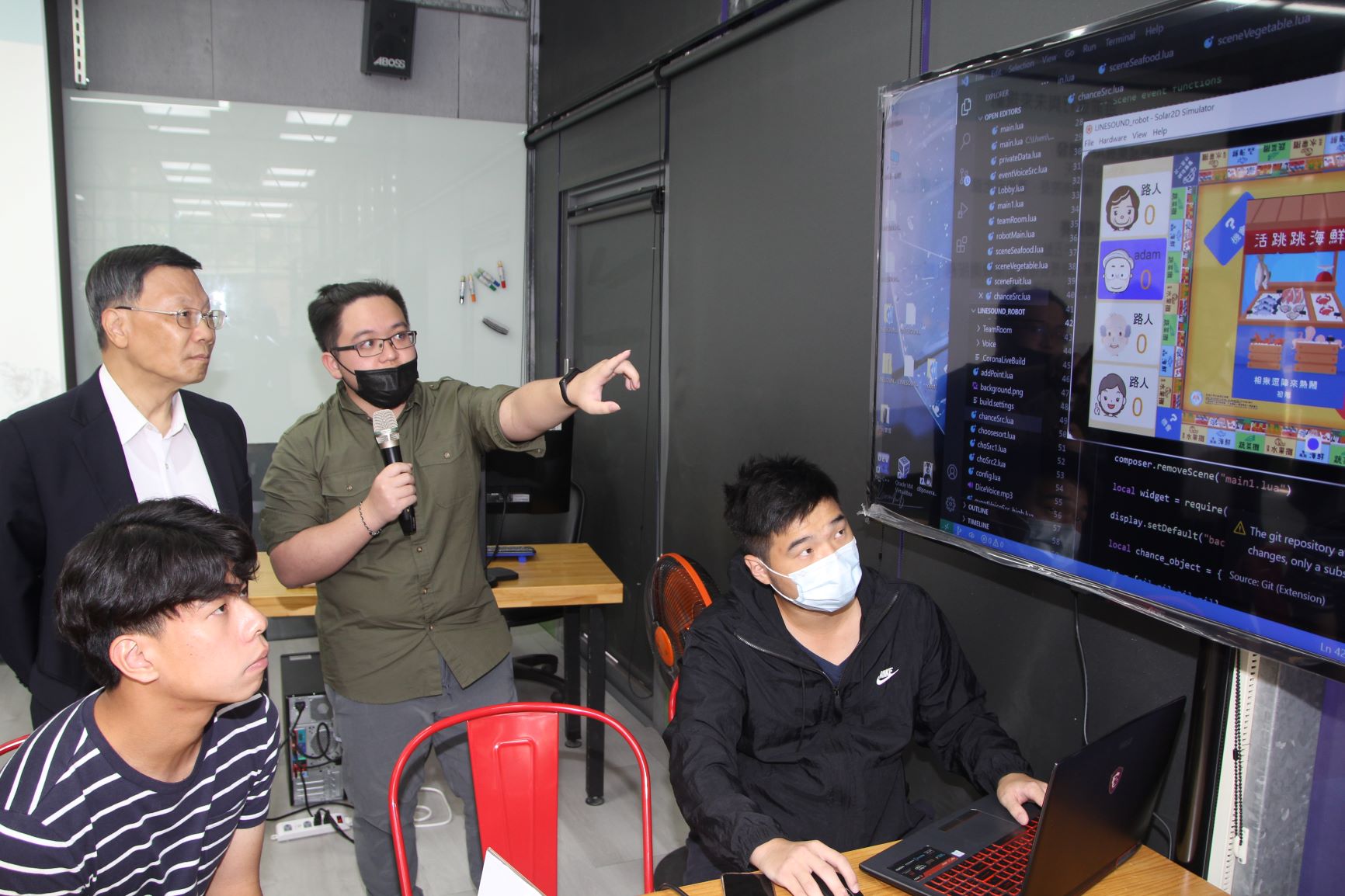 蔡進發校長(左)聽取資工系姜宏翰同學(左二)，報告防失智手遊「Line sound」APP的各種玩法。